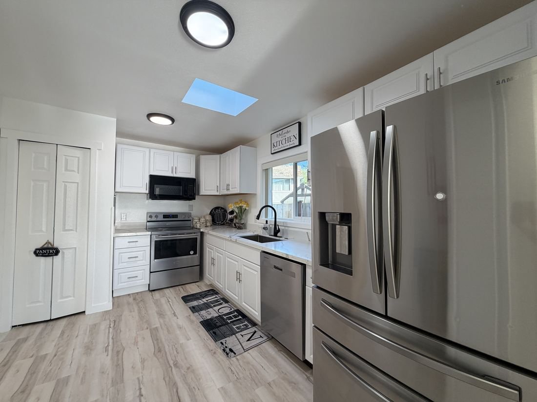 The kitchen, with white cabinets, a stainless steel refrigerator and a stove.